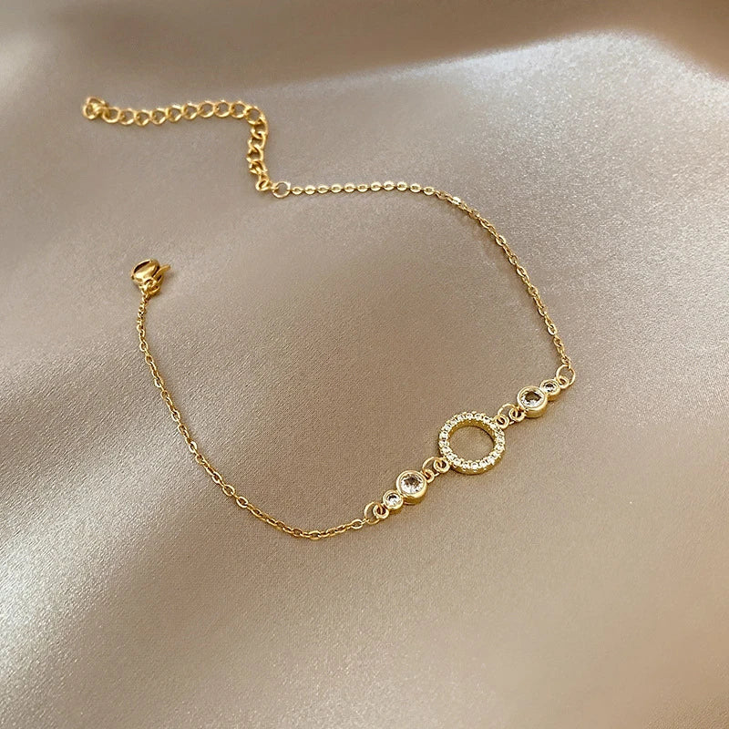Pulseira "Elo Dourado Aurum Royale" – Um clássico que nunca sai de moda, esta pulseira em corrente fina dourada é adornada por um delicado círculo cravejado de cristais brilhantes, simbolizando a união e a eternidade. Sofisticada e minimalista, é a escolha perfeita para quem deseja um toque de brilho sem perder a sutileza.