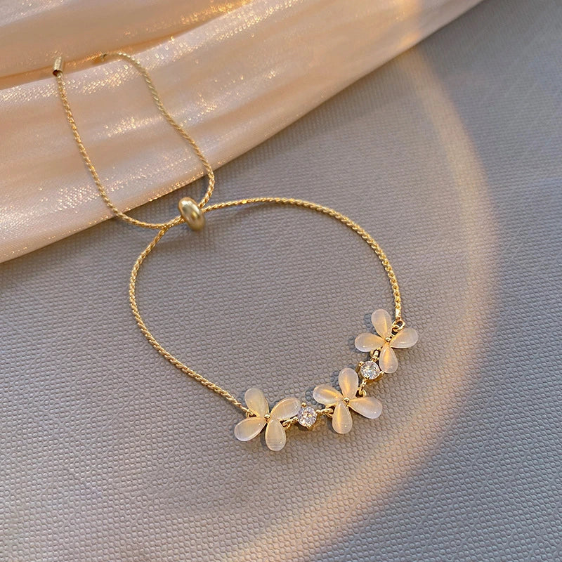 Pulseira "Flores do Amanhecer Aurum Royale" – Uma peça delicada e encantadora, esta pulseira apresenta flores esculpidas em tons opalinos que refletem a suavidade da luz do amanhecer. Com cristais brilhantes intercalados, é uma joia que exala feminilidade e sofisticação, perfeita para ocasiões especiais ou para trazer um toque romântico ao seu dia a dia.