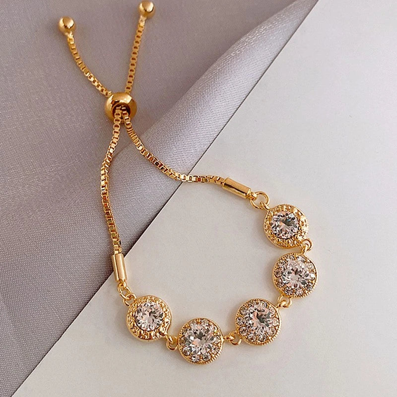 Pulseira "Aurum Royale Luz Divina" – Um acessório sofisticado que captura a essência do glamour. Com cinco pedras brilhantes cravejadas em molduras douradas, esta pulseira exala elegância e refinamento. Perfeita para adicionar um toque de luxo ao seu dia ou ocasiões especiais, como casamentos, festas ou presentes memoráveis.